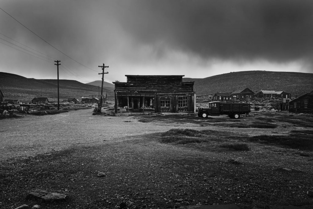 Old building exterior with stormy sky and truck in Bodi, California ghost town