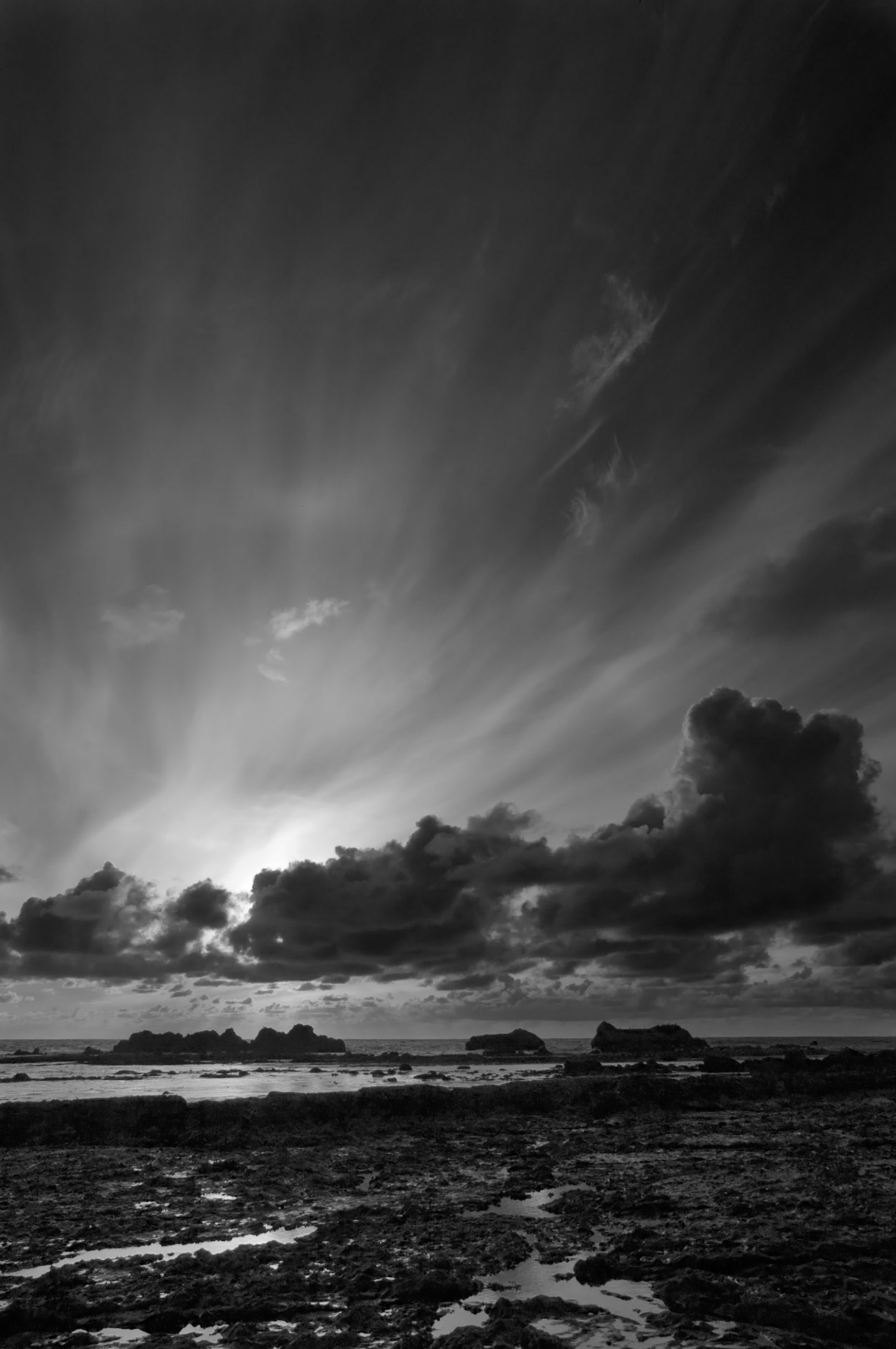 Beach with rocks and streaked clouds