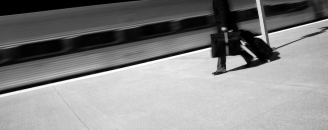 Traveler walking with suitcases next to moving train