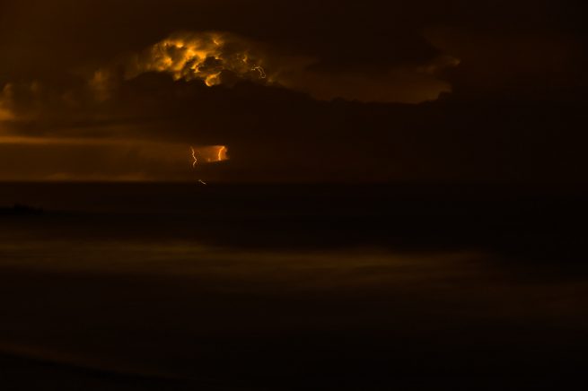 Lighting bolt at night over ocean