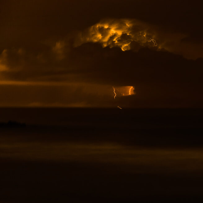 Lighting bolt at night over ocean