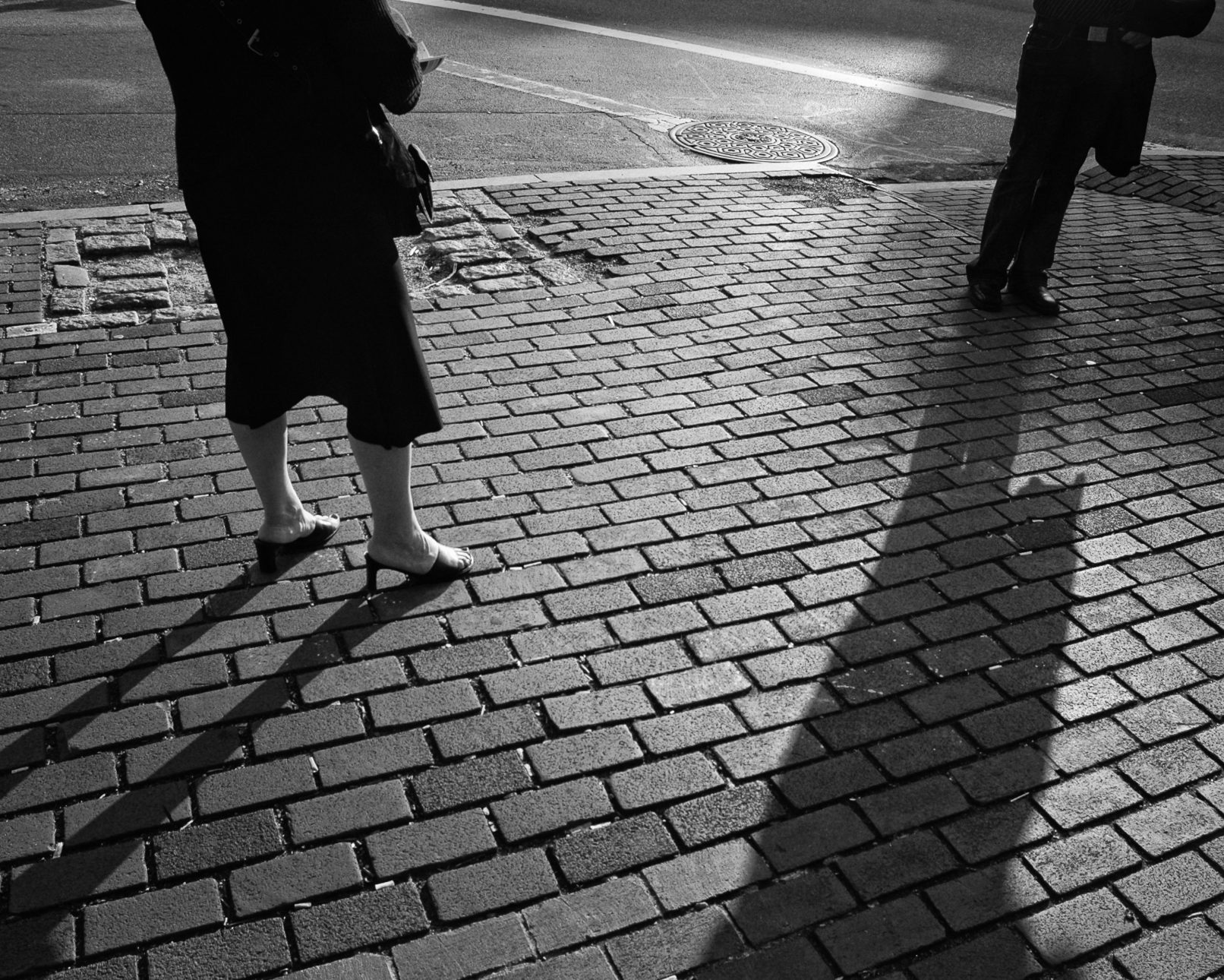 Two people on city street with long shadows