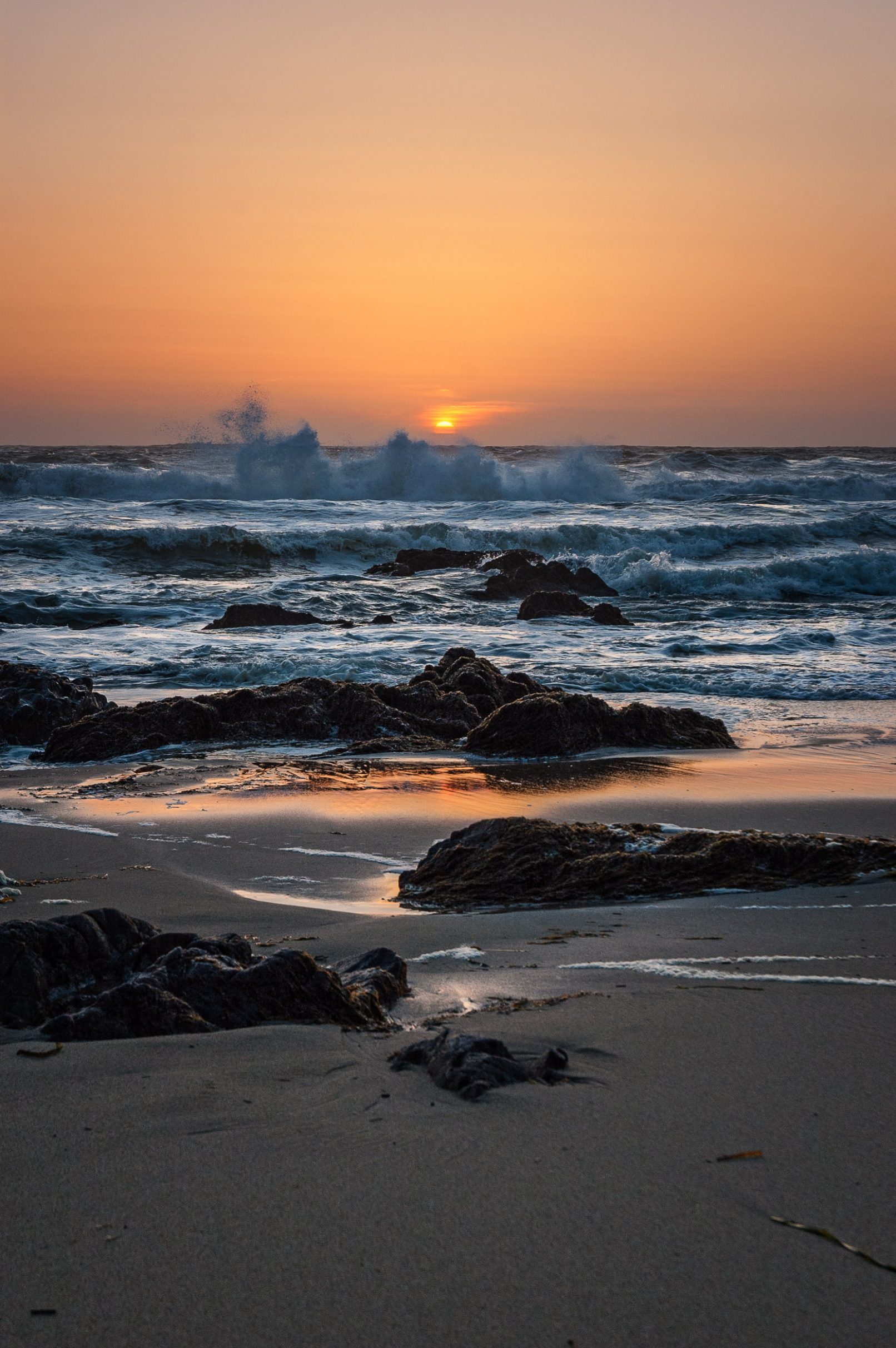 Sunset at California beach with waves and rocks