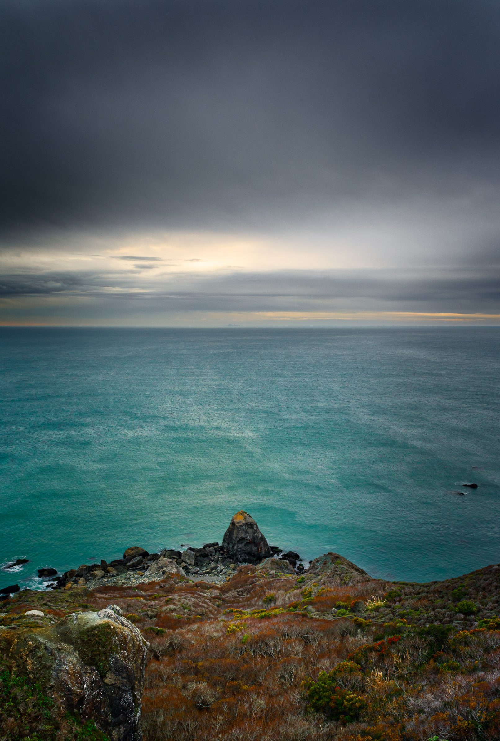 Pacific Coast cliff rock with ocean and glow in clouds
