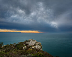 California coast cliff rock and ocean with storm in distance