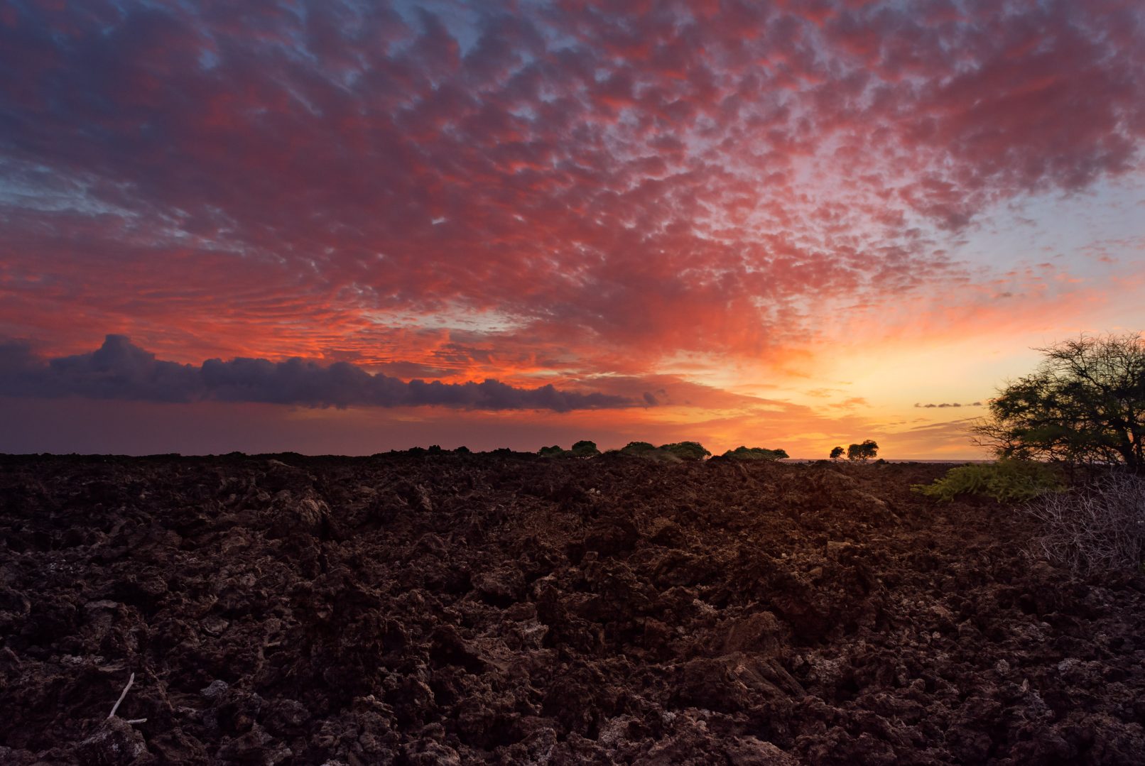 Hawaii, lava rock field with colored clouds and sunset between Mahai'ula Beach and Makalawena Beach