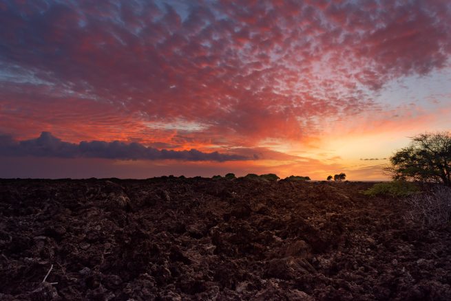 Hawaii, lava rock field with colored clouds and sunset between Mahai'ula Beach and Makalawena Beach