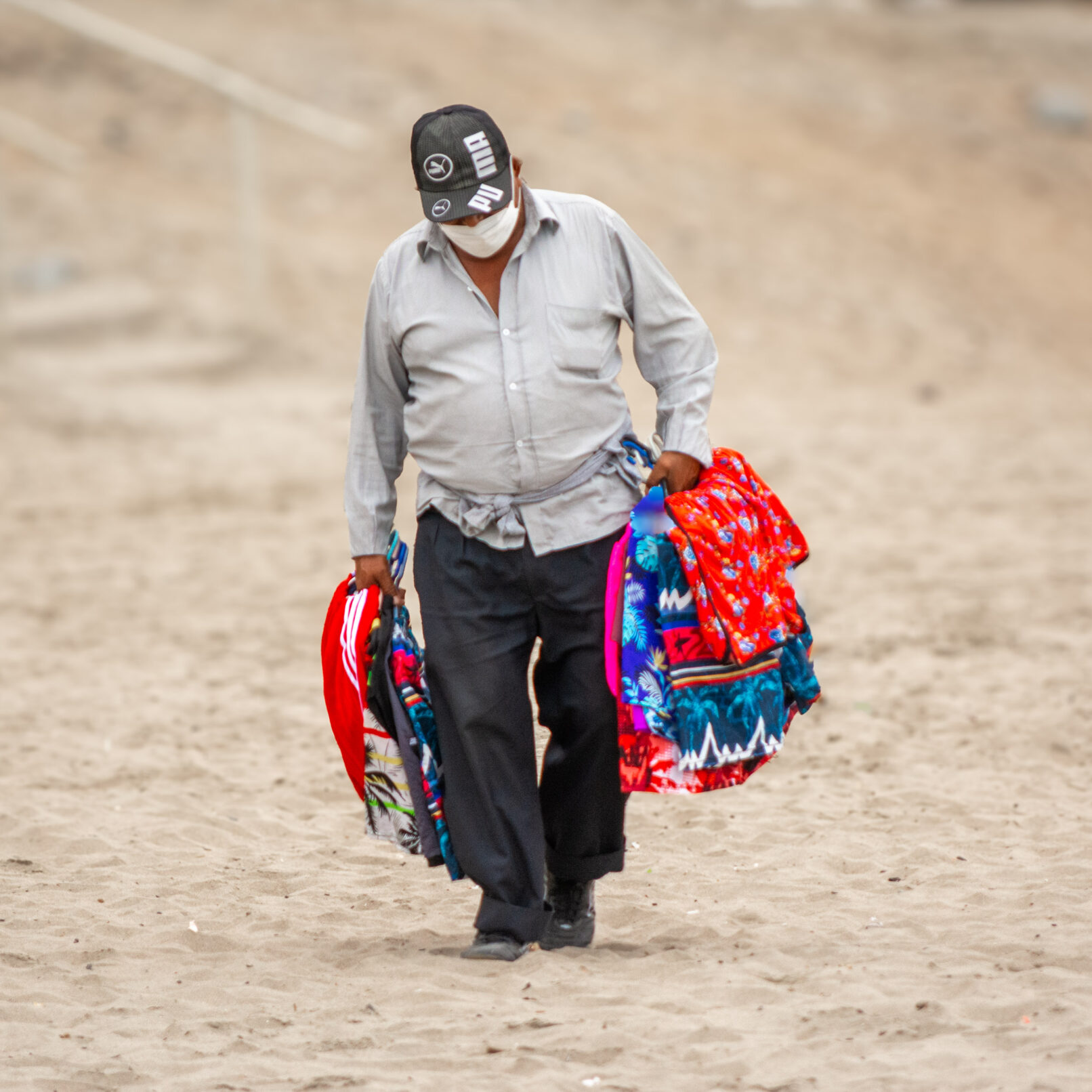Man on beach carrying clothes in Lima, Peru